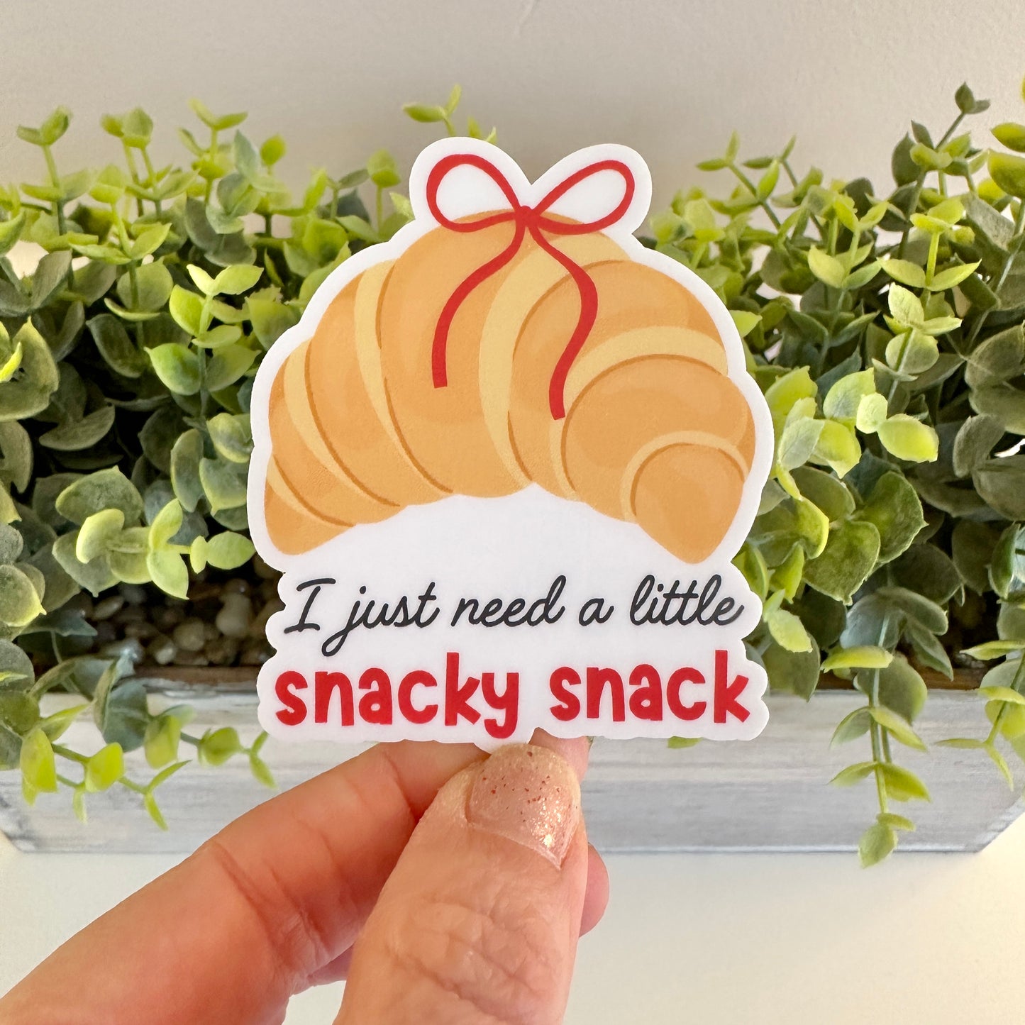 foodie gift sticker with text 'I just need a little snacky snack' held in hand