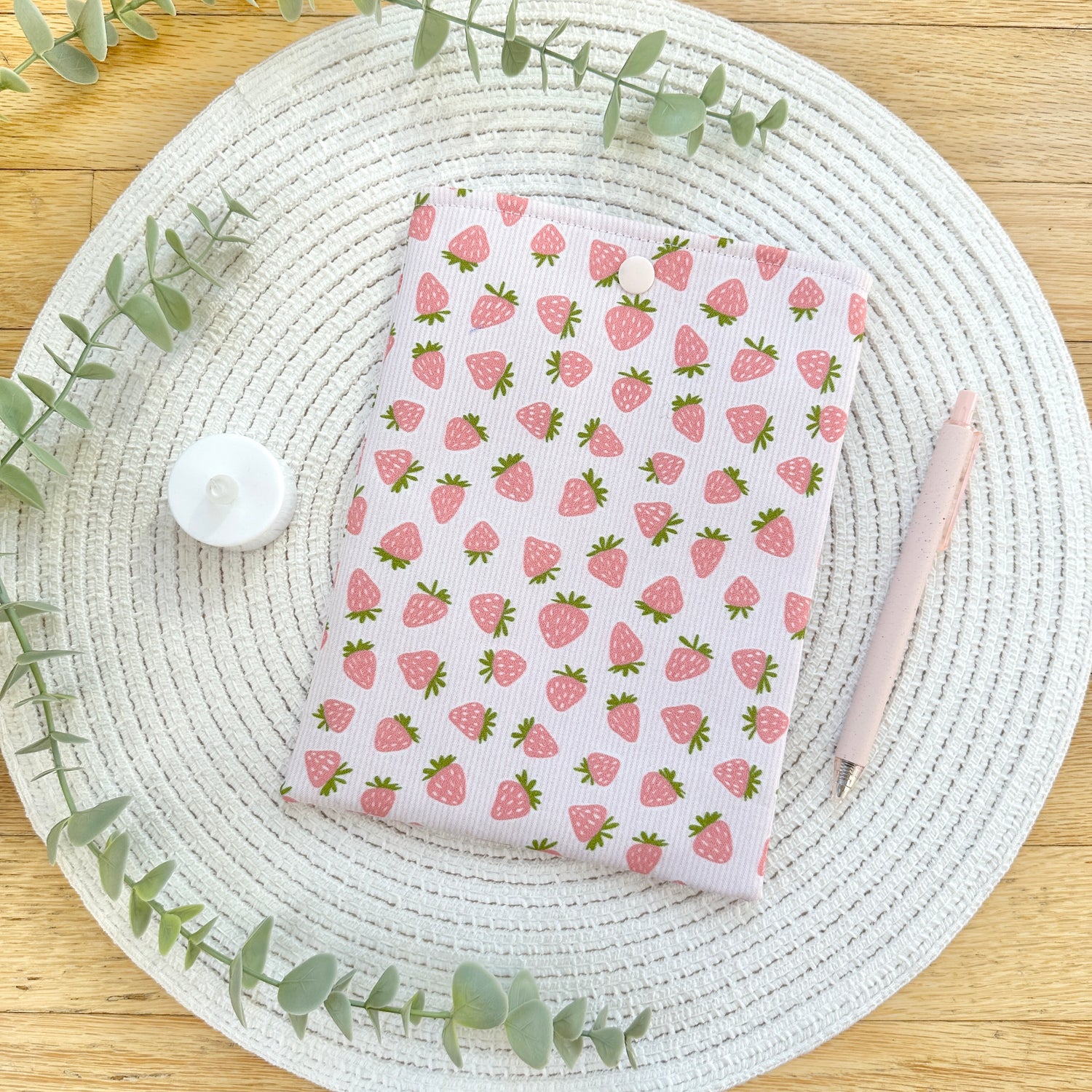 strawberry-patterned kindle sleeve on table with pen and candle