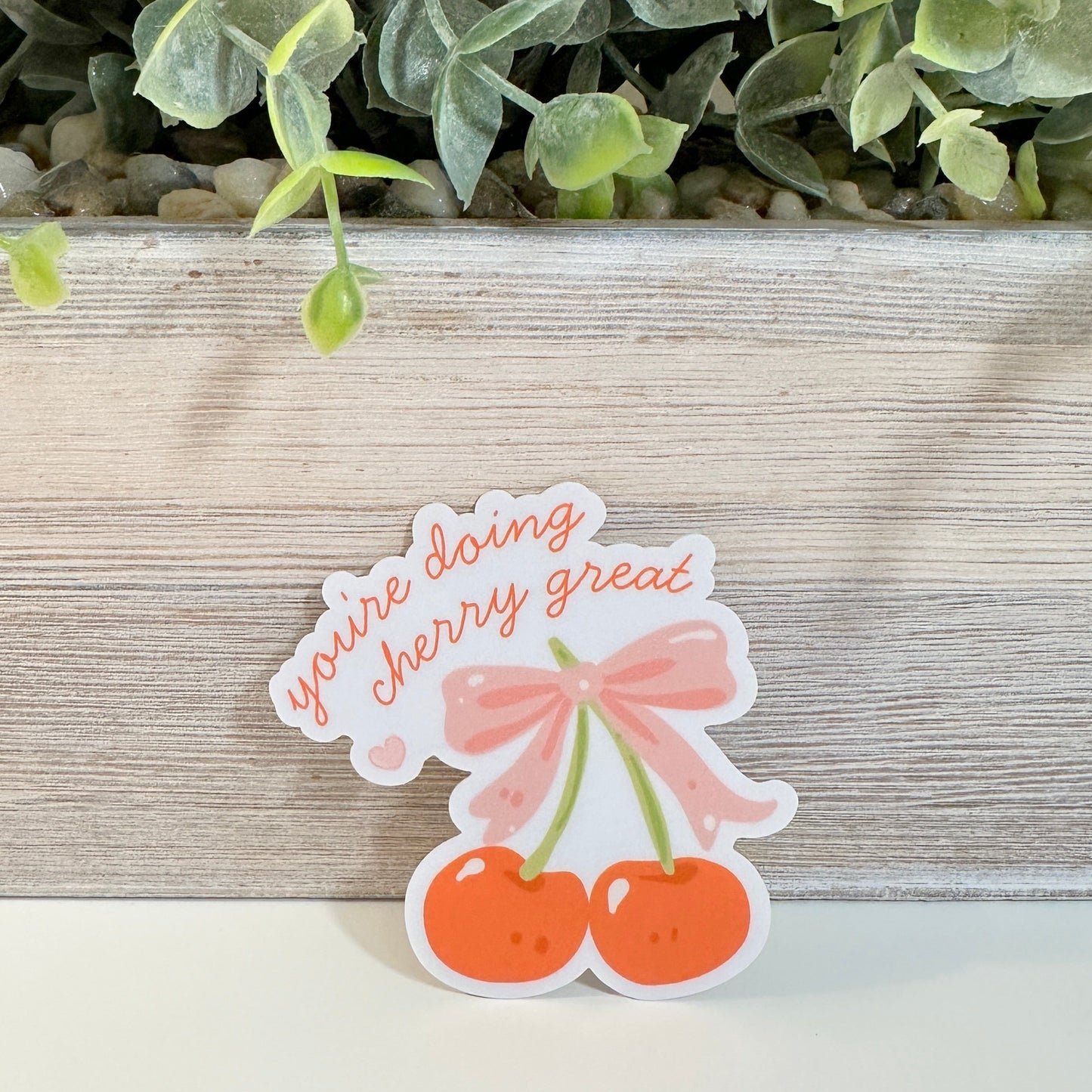 a waterproof positive affirmations decal sits against a planter on a white tabletop.