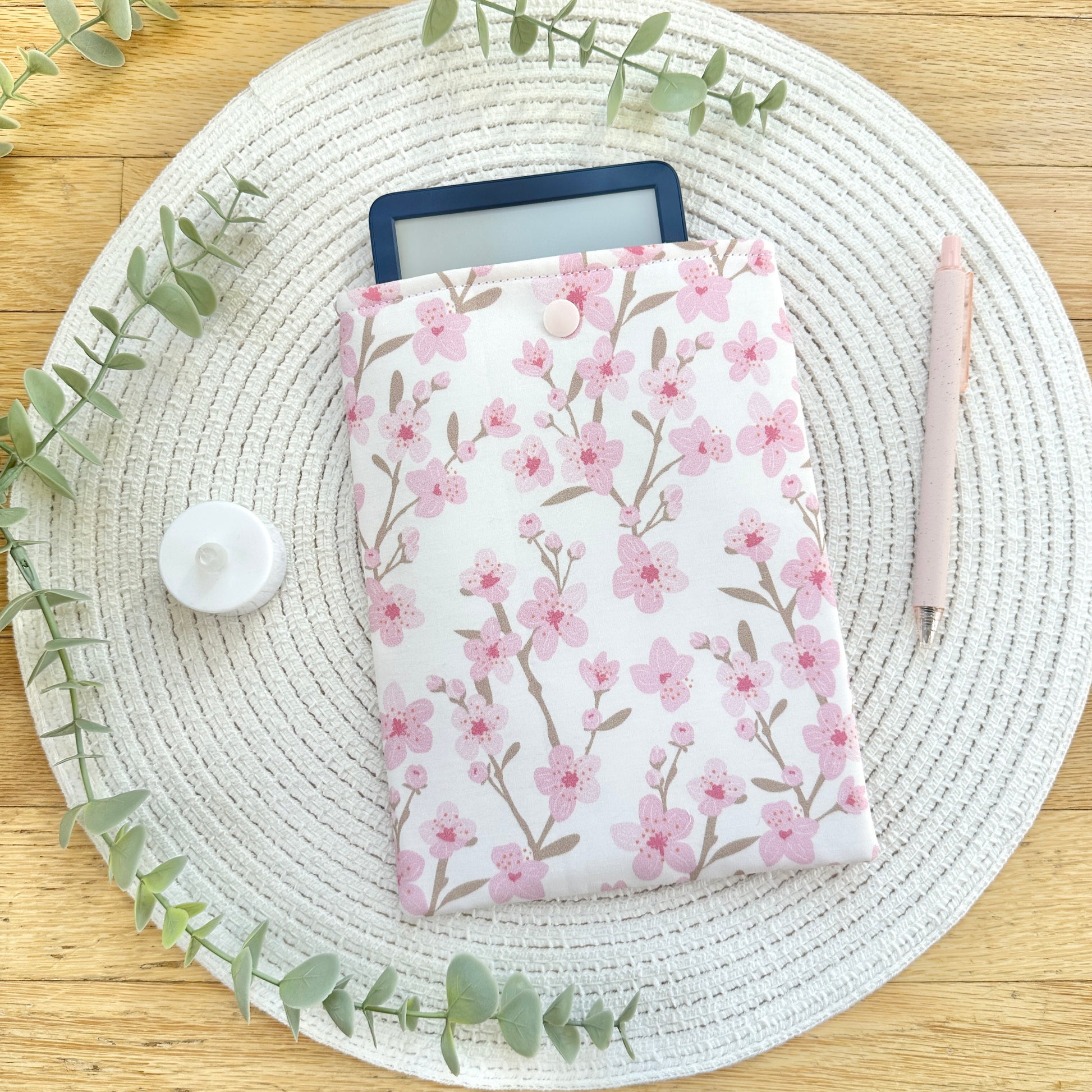 floral-patterned kindle sleeve on woven mat with decorative elements
