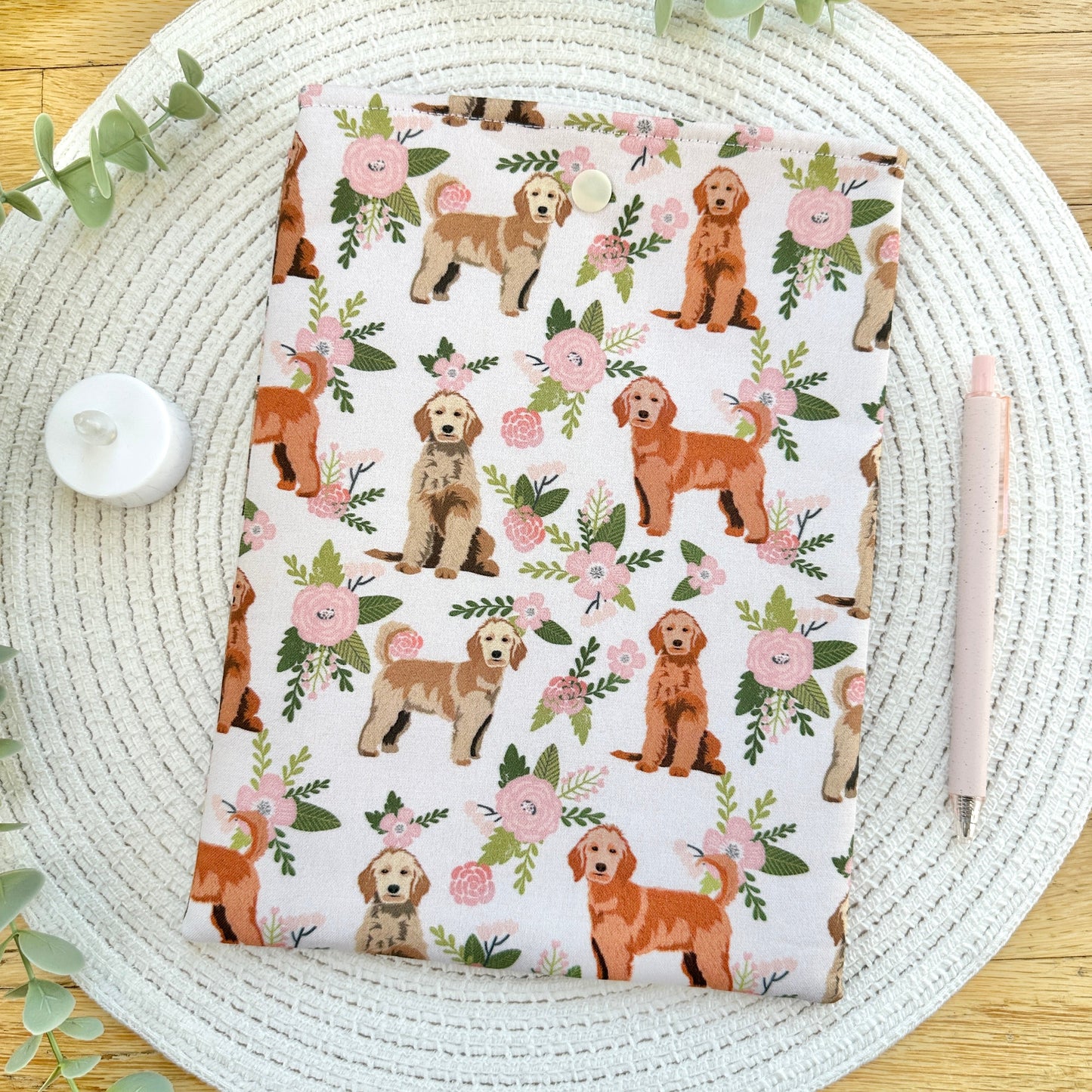 floral- and dog-themed sewn cotton book sleeve on woven mat with decorative elements