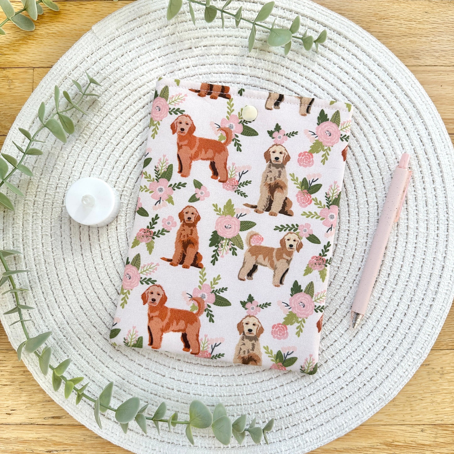 floral and puppy themed e-reader sleeve on table with greenery and pen