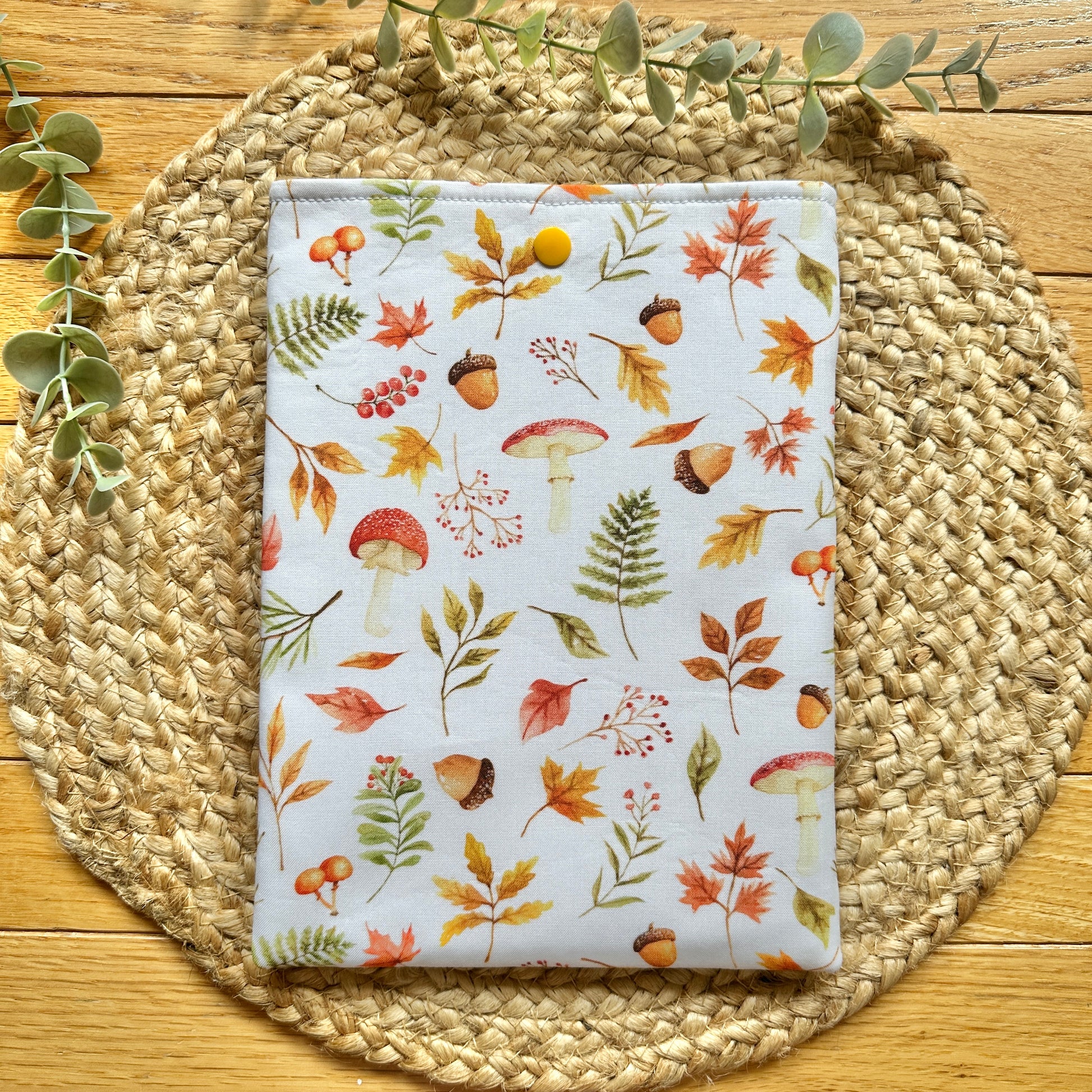 fall-themed decorative cotton book sleeve on woven placemat with greenery
