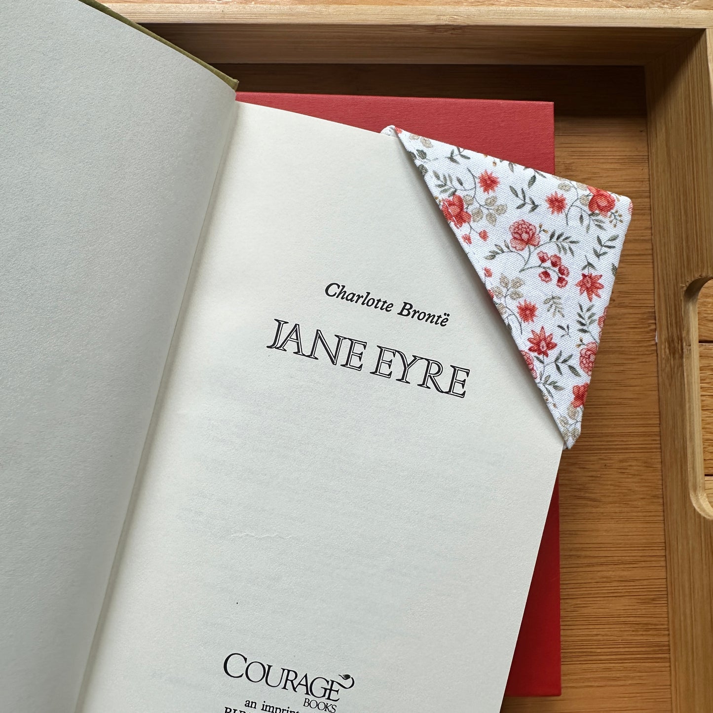 fall-themed corner bookmark in use in a book on a wooden tray