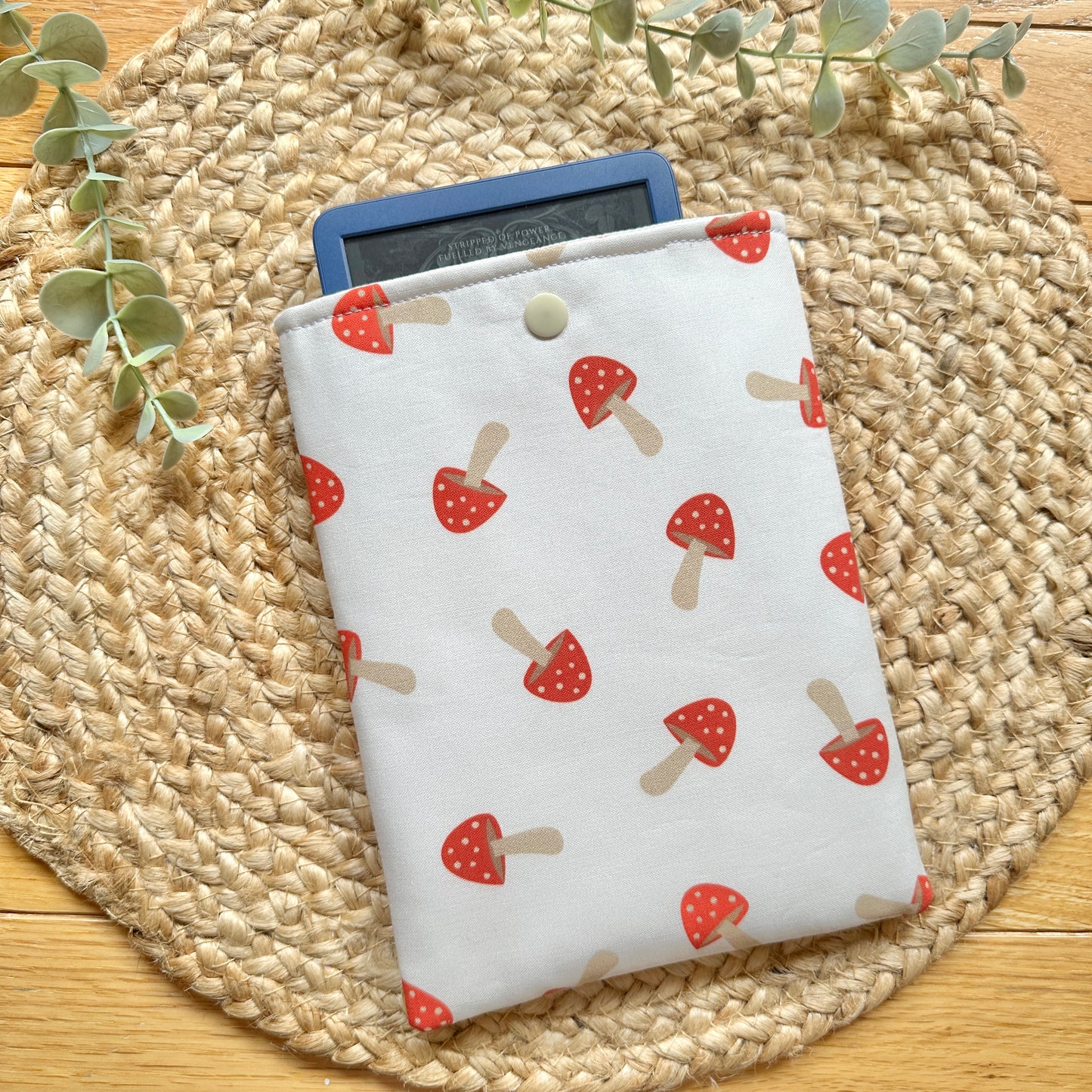 a mushroom-themed e-reader sleeve on a woven placemat