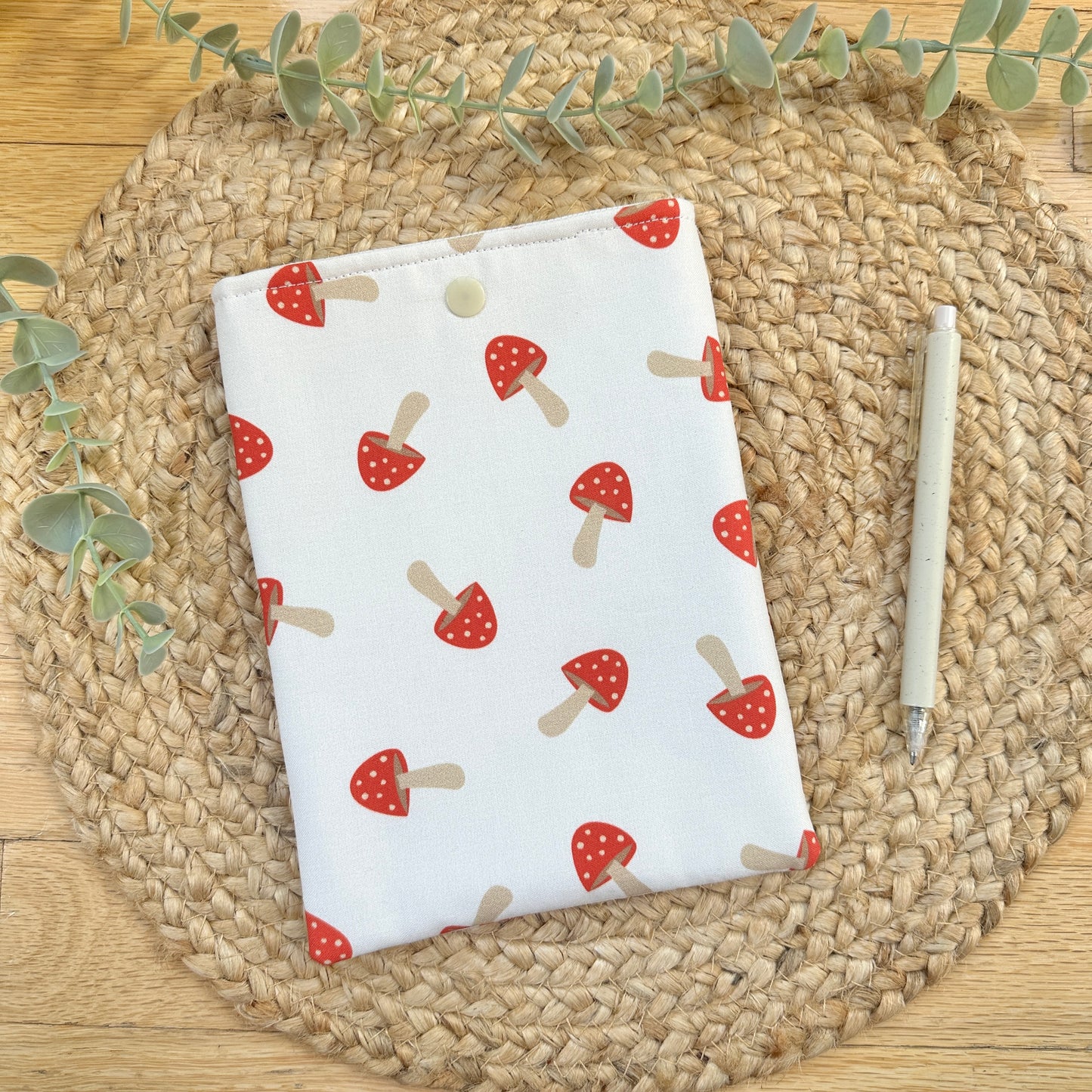 sewn fungi-themed fabric e-reader sleeve  styled on woven placemat with greenery