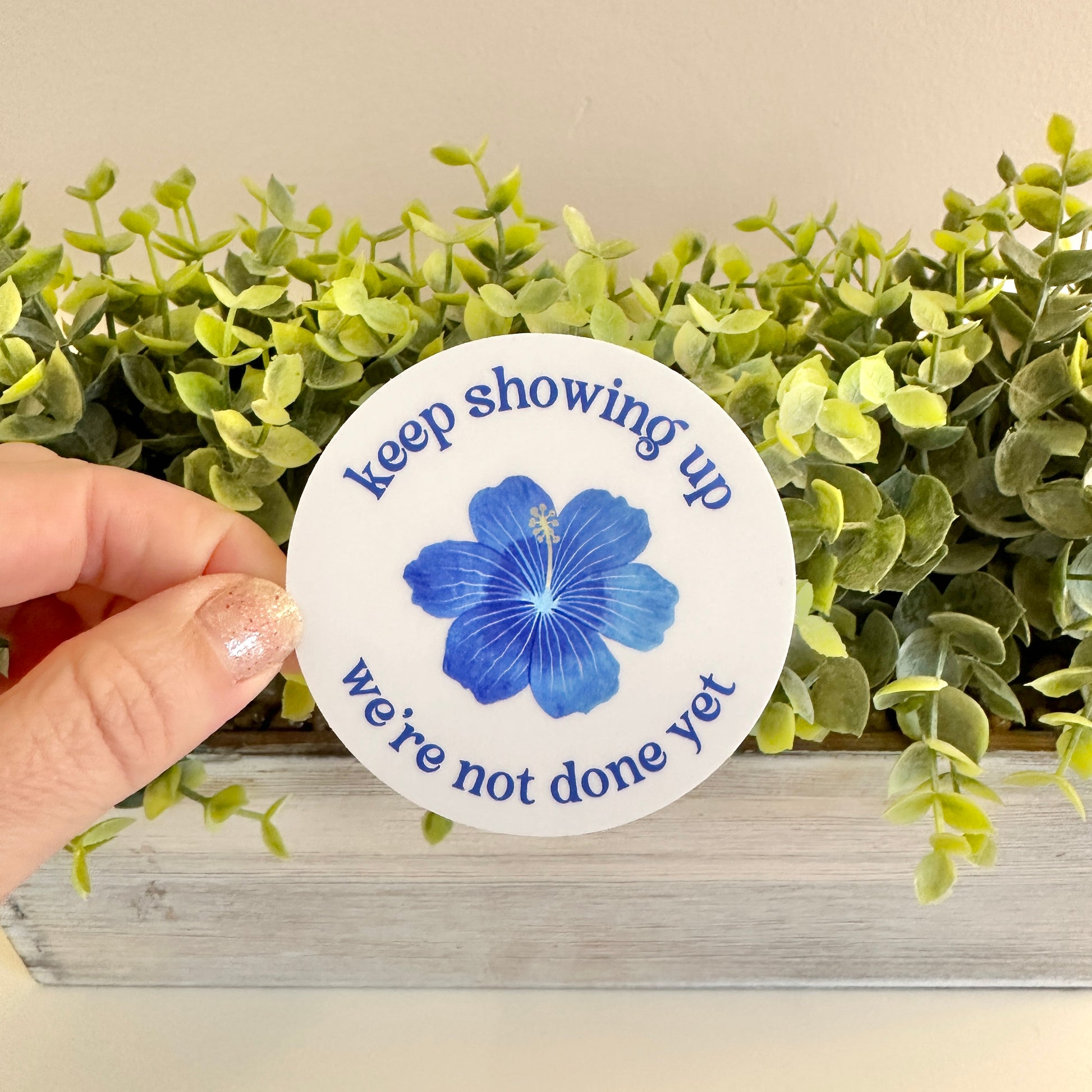 subtle democrat circle-shaped sticker with blue flower and message to keep fighting for good