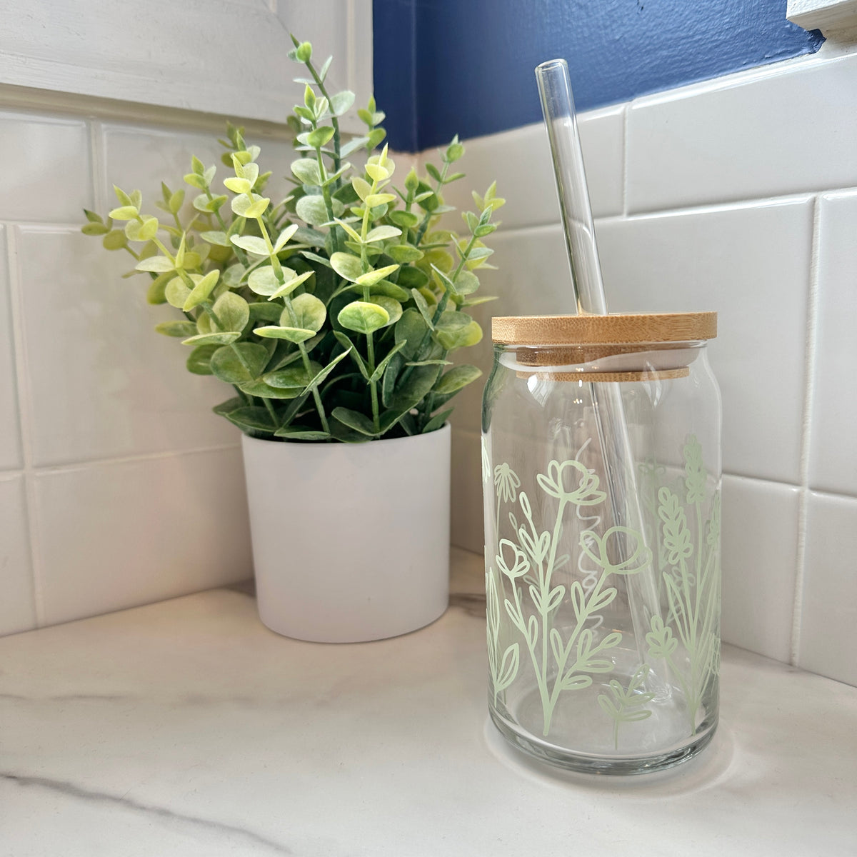 decorative iced coffee glass cup on marble surface with green plant in the background