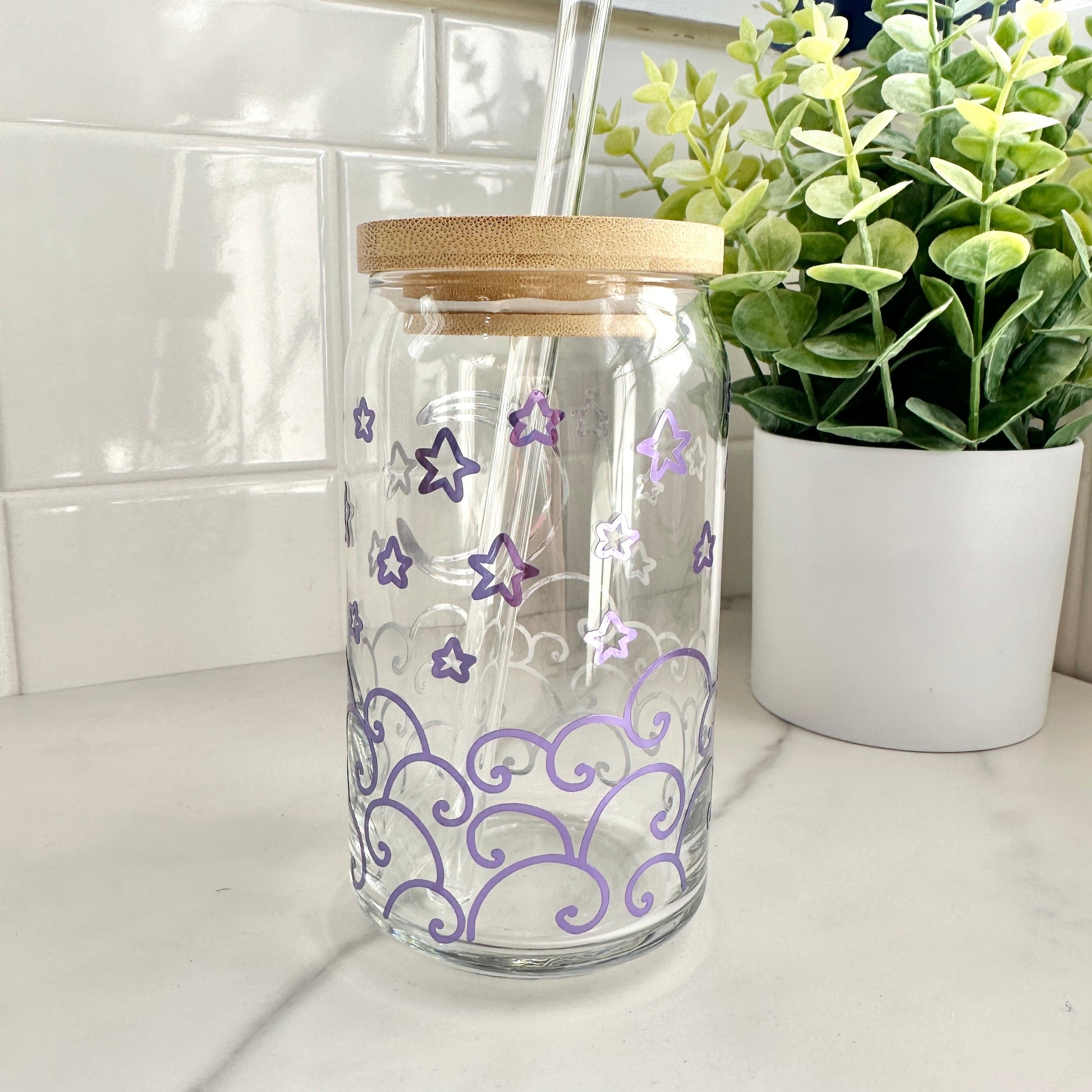 Moon and waves iced coffee glass cup on a countertop with a plant in the background