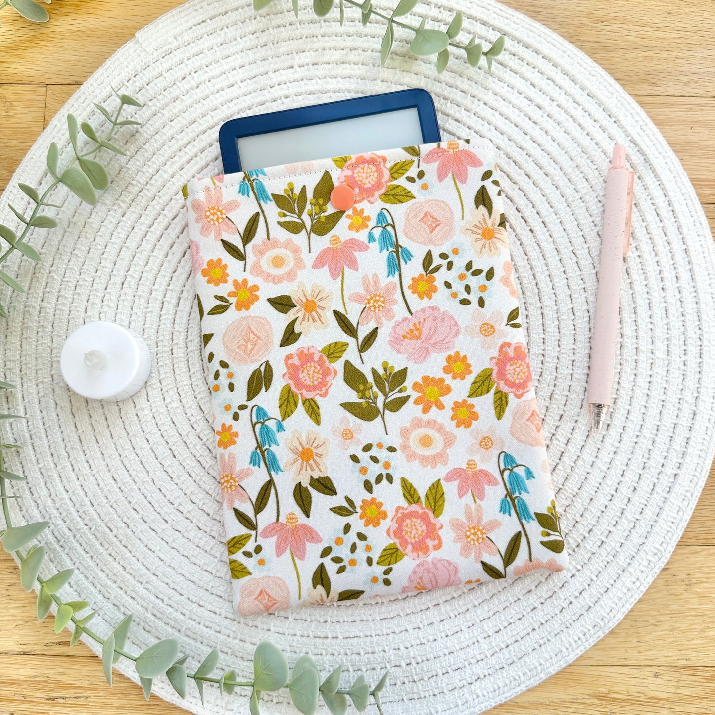 floral-patterned cotton e-reader sleeve on table with pen and candle