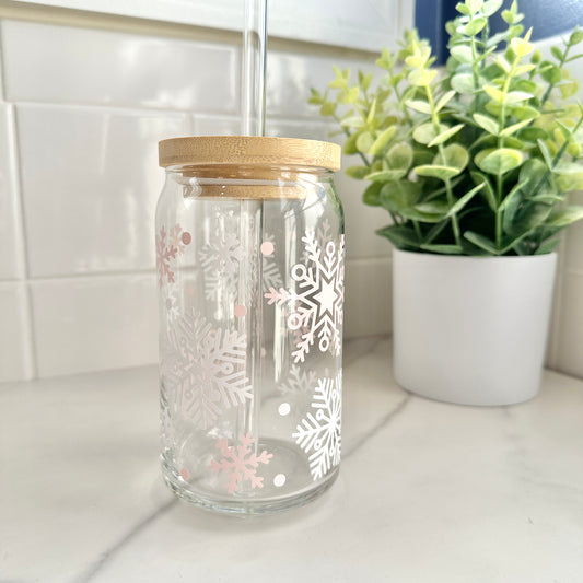 Glass coffee cup with snowflake designs and a wooden lid on a kitchen counter.