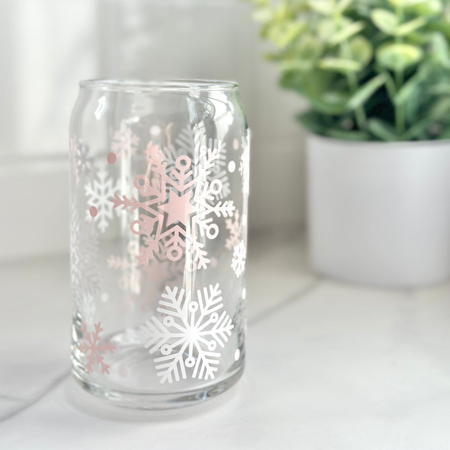pink and white snowflakes glass cup on counter with plant in the background