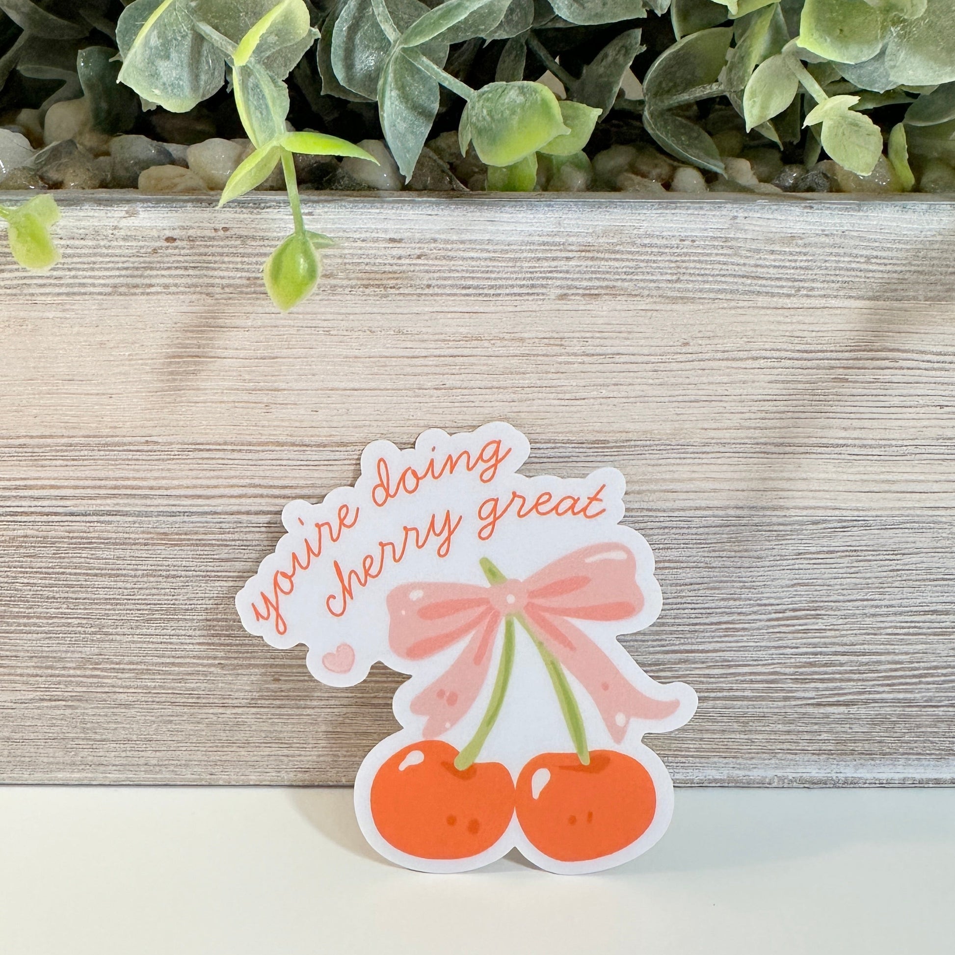a waterproof positive affirmations decal sits against a planter on a white tabletop.